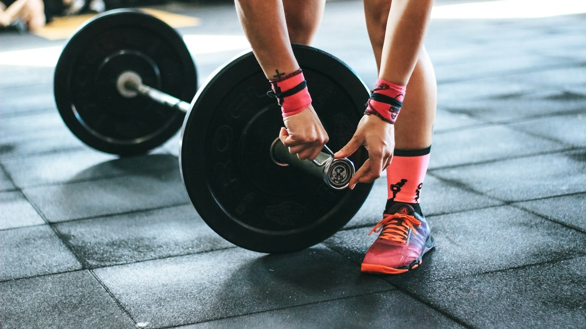 person locking gym plates on barbell
